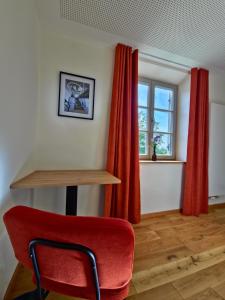 ein roter Stuhl in einem Zimmer mit Fenster in der Unterkunft Hotel im Sud in Eggenfelden