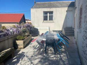a table and chairs on a patio in front of a house at Maison de Tisserand 10 pers in Gesté