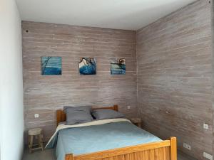 a bedroom with a bed with three pictures on the wall at Maison de Tisserand 10 pers in Gesté