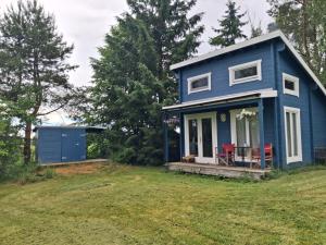 a blue house with red chairs on a yard at Koobamäe saunamaja in Kulli