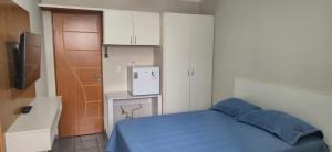 a small bedroom with a blue bed and a refrigerator at Studio GT in São Carlos