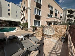 a patio with chairs and a pool and a building at Camere de inchiriat KATALEYA in Mamaia Sat/Năvodari