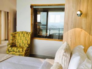 a bedroom with a bed and a chair and a window at RUBONA HILL Lodge in Gisenyi