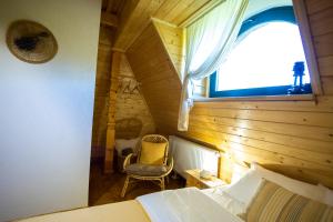 a bedroom with a bed and a window and a chair at DejaView Cabin&Camp in Rogojel
