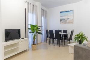 a living room with a tv and a table with chairs at Royal Suites Estepona by Croma in Estepona