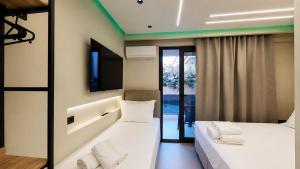 two beds in a room with a tv on the wall at Troy Seaside in Paralia Katerinis