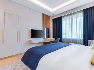 a bedroom with a large bed and a tv at Mövenpick Grand Al Bustan in Dubai +269 photos