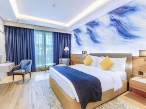 a hotel room with a bed and a desk at Mövenpick Grand Al Bustan in Dubai