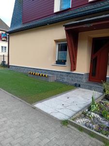 a house with a red door and a grass yard at Ferienwohnung mit Garten und Spielplatz in Klingenthal +2 photos