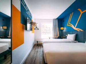 a room with three beds and a wall with orange and blue at ibis Styles Poços de Caldas in Poços de Caldas