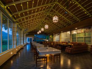 a restaurant with tables and chairs and windows at The Hosteller Coorg, Madikeri in Madikeri