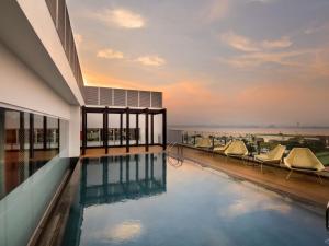a swimming pool on the roof of a building with chairs at Novotel Kinshasa La Gombe in Kinshasa
