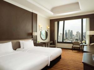 a hotel room with two beds and a large window at Grand Mercure Bangkok Atrium in Bangkok +160 photos
