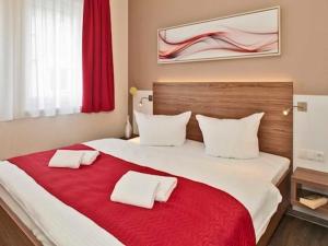 a bedroom with a large bed with a red blanket at Dünenhaus Aurell, App 4 mit Sauna in Heringsdorf