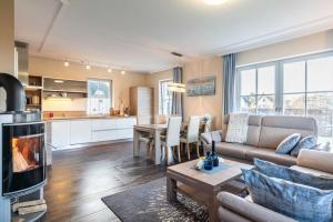 a living room with a couch and a table with a fireplace at Ferienhaus Strandmuschel mit Sauna in Loddin