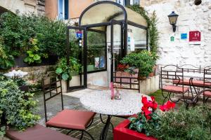a patio with a table and chairs and plants at Hôtel La Muette in Arles
