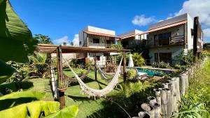 a resort with a hammock in front of a house at Jangadas do Toque Milagres Flats no Térreo in São Miguel dos Milagres