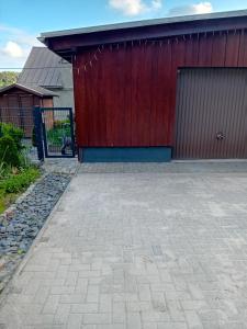 a garage with a red door and a brick driveway at Ferienwohnung mit Garten und Spielplatz in Klingenthal