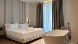 a hotel room with a white bed and a chair at Golden Nina Hotel in Vlorë