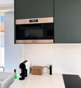 a kitchen with a microwave above a white counter at Casa da Loja in Marinha Grande