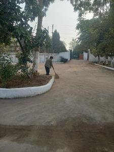 a person sweeping a driveway with a broom at Lighthouse Villa Homestay in Dimapur