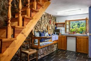 a kitchen with wooden stairs and a stone wall at Casa Engracita in Valle de Lago
