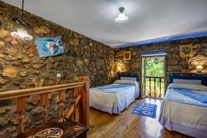 a bedroom with two beds and a stone wall at Casa Engracita in Valle de Lago