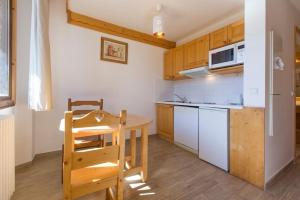 a small kitchen with a table and a refrigerator at Résidence La Grande Cordée - Combloux in Combloux