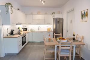 a kitchen with white cabinets and a table with a bowl of fruit on it at Luxury Villa Yvonni in Poros