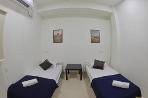 a room with two beds and a chair in it at Slackpackr Malakpet Hyderabad in Hyderabad