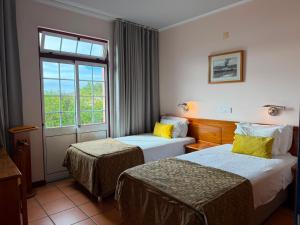 a hotel room with two beds and a window at Apartamentos Turisticos Verdemar in Horta