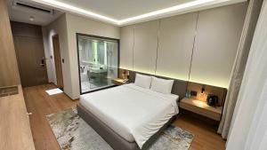 a bedroom with a white bed and a bathroom at The Villas Hotel in Pleiku