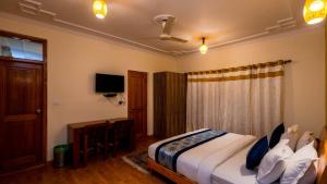 a bedroom with a bed and a desk and a television at Hotel Om Ladakh in Leh