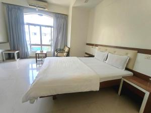 a large white bed in a room with a large window at Hotel Rajtara in Satara +1 photo