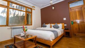 a bedroom with a bed and a table and a window at Hotel Om Ladakh in Leh +72 photos