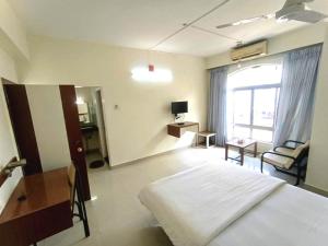 a bedroom with a bed and a desk and a window at Hotel Rajtara in Satara