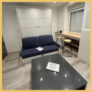 a living room with a blue couch and a table at Studio tout équipé in Vaugneray
