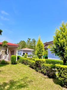 a house with a yard with bushes and trees at Corbett VEDA INN in Rāmnagar