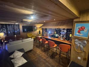 a living room with a bar with a couch and chairs at Logis Hôtel Le Cairn in Les Deux Alpes +28 photos
