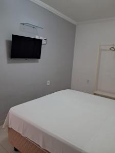 a white room with a flat screen tv on the wall at Pousada Mar dos Sonhos in Paripueira