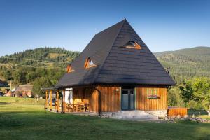 a small house with a black roof on a field at DejaView Cabin&Camp in Rogojel