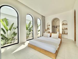 a bedroom with a large bed with large windows at The Young Villas - 1 Bedroom Villas, Bingin in Uluwatu