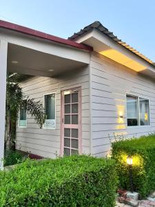 a white house with a bush in front of it at Corbett VEDA INN in Rāmnagar