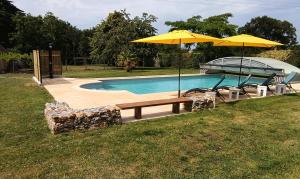 a swimming pool with a bench and an umbrella at Bed and Breakfast en Sarthe in Avoise