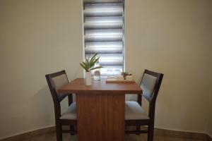 a wooden table with two chairs and a window at Casa by Cosy Concept in Trivandrum