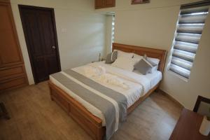 a bedroom with a large bed with white sheets at Casa by Cosy Concept in Trivandrum