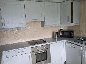 a kitchen with white cabinets and a stove top oven at Alex in Castlerea