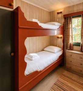 two bunk beds in a small room with a window at Briskebu, cosy cabin by ski slopes in Geilo