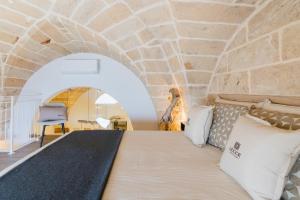 a bed in a room with a stone wall at Melodia del Salento - Lecce Selection in Surbo