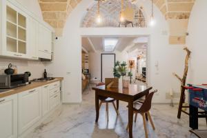 a kitchen with white cabinets and a wooden table at Melodia del Salento - Lecce Selection in Surbo +14 photos